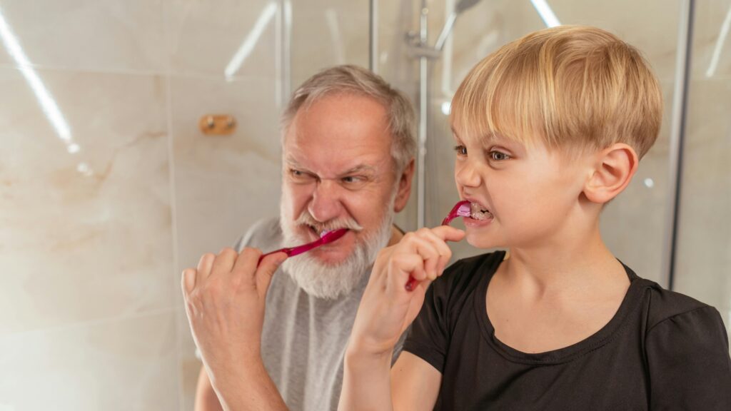 Grandfather and grandson brushing teeth, promoting family bonding and oral hygiene habits.